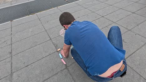 hombre creando dibujos de tiza colorida en el pavimento