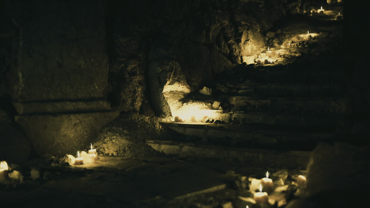 Escadaria antiga banhada pela luz fraca de velas, com elementos rituais