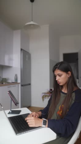 mujer trabajando desde casa en una computadora portátil en la cocina