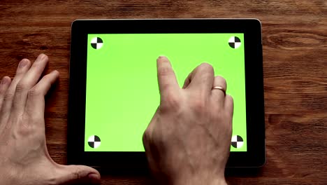 usando una tableta con pantalla verde en una mesa de madera. filmado en 4k, uhd