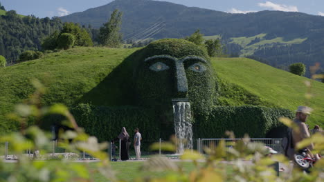 a giant green sculpture of a face with a waterfall pouring out of its mouth