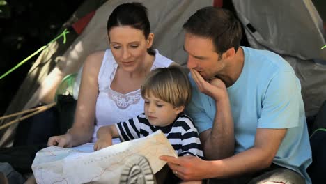 Family-looking-at-a-map-near-a-tent