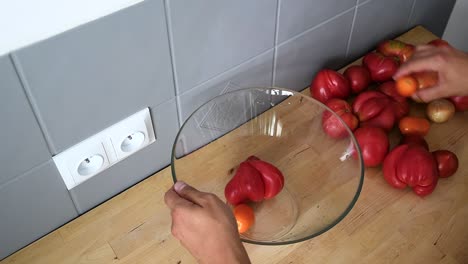 primer plano de manos masculinas poniendo tomates rojos frescos en un recipiente de vidrio