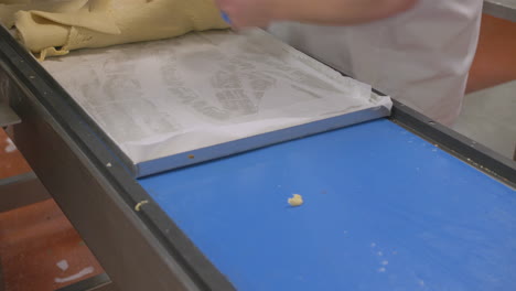 a sheet of pastry on a production line comes out misshaped as a worker rolls up the scraps for repurposing