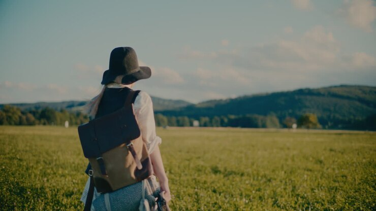 Woman Walking In Meadow Carrying Backpack