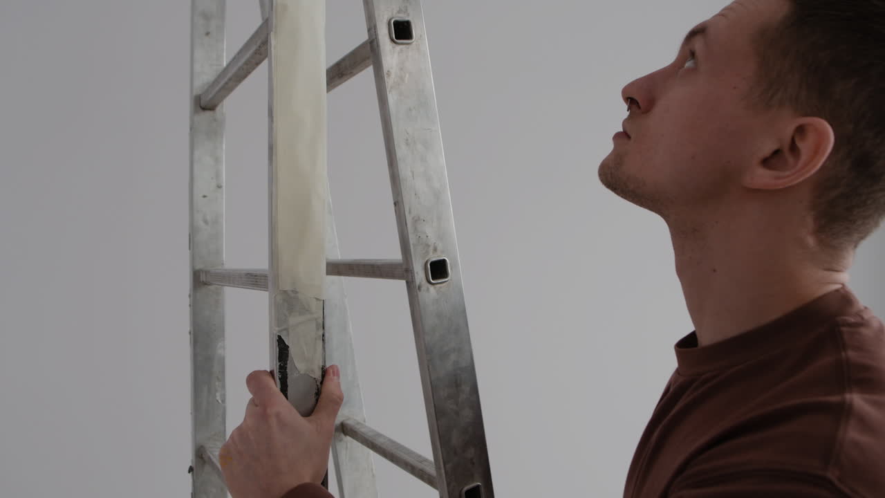 Man Carrying a Ladder and Removing Tape