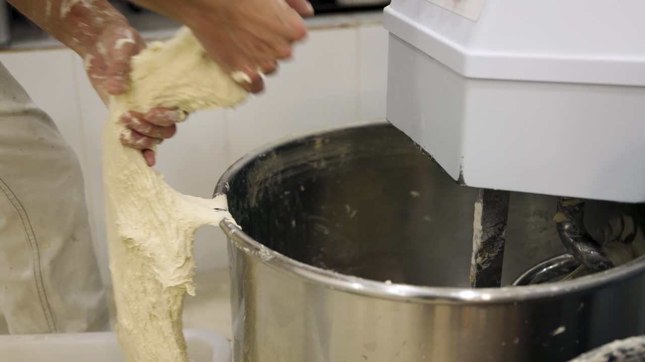 Baker Removing Fresh Dough from Industrial Mixer