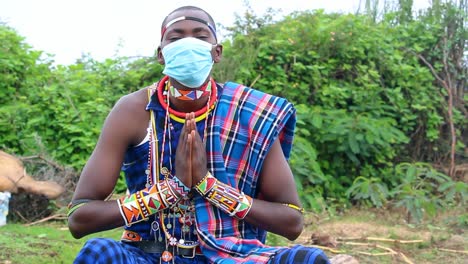 african man wearing a protective face mask in a traditional maasai attire greets