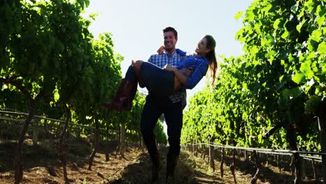 Man-carrying-woman-while-walking-through-vineyard