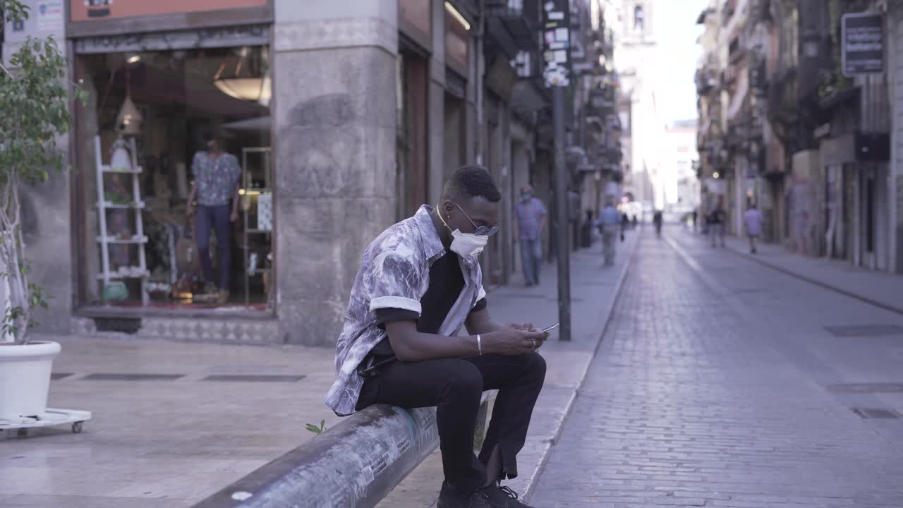 Man using a smartphone outdoors while wearing a mask