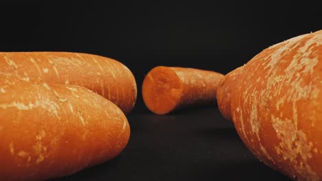 close up dolly in slider shot of fresh organic orange carrots isolated on dark background