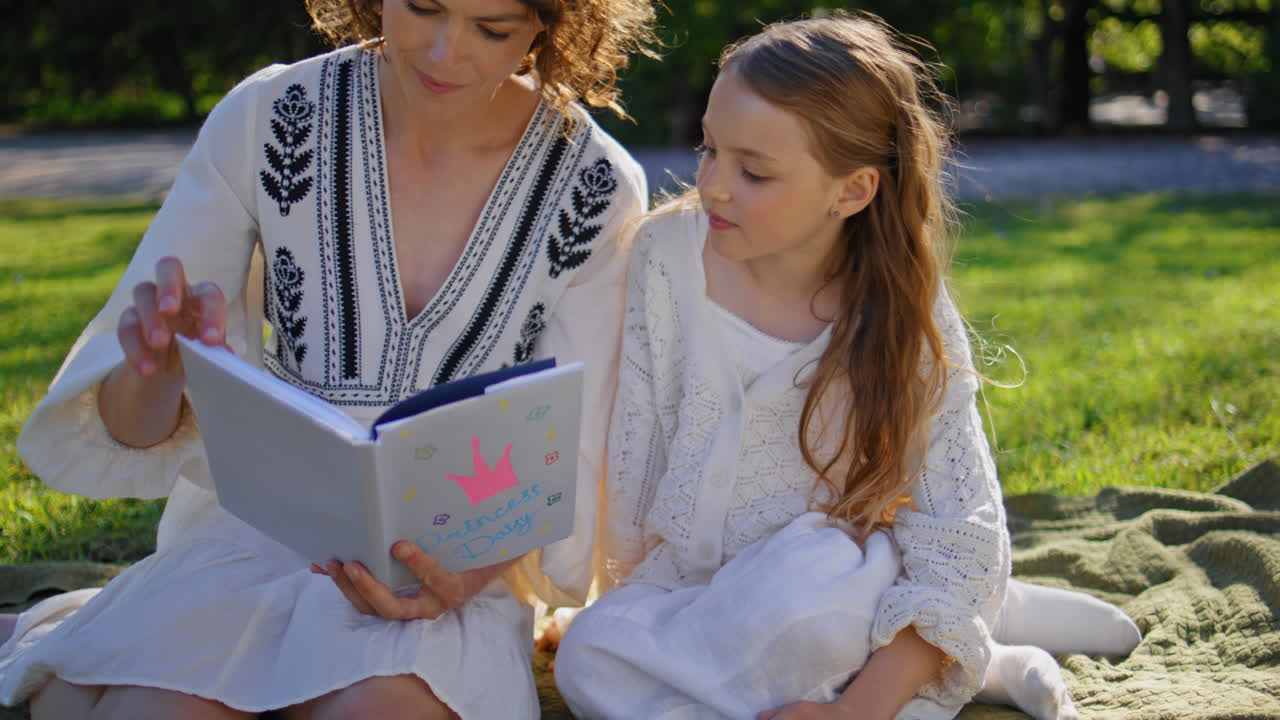 Picnic family reading book resting together at summer weekend nature closeup