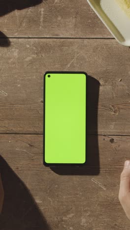 Vertical-Video-Overhead-Shot-Of-Person-Waiting-Whilst-Green-Screen-Mobile-Phone-Buffers