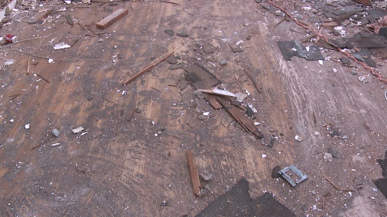 철거되는 과정에서 집의 노출된 기둥과 부서지는 벽을 보여주기 위해 파편으로 덮인 바닥에서 위로 기울입니다.