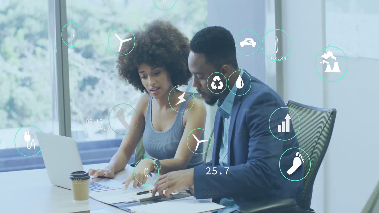 Animation of multiple icons over diverse coworkers discussing reports on desk in office