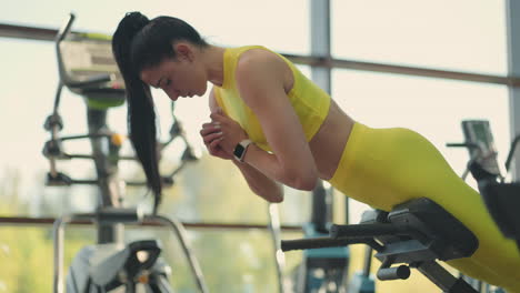 young beautiful hispanic woman performs hyperextension in the gym. the determined woman performs the back extension at the bench in the gym. intense masculine energy. healthy lifestyle. sport concept