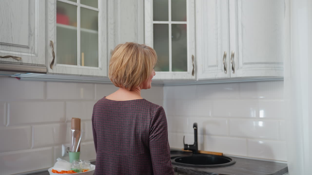 옷을 입은 우아한 여성이 부으로 들어가서, 따뜻한 미소로 캐비을 뒤집고 휴식을 취하고, 배경에서 책을 읽는 사람이 편안하고 평화로운 순간을 포착합니다.