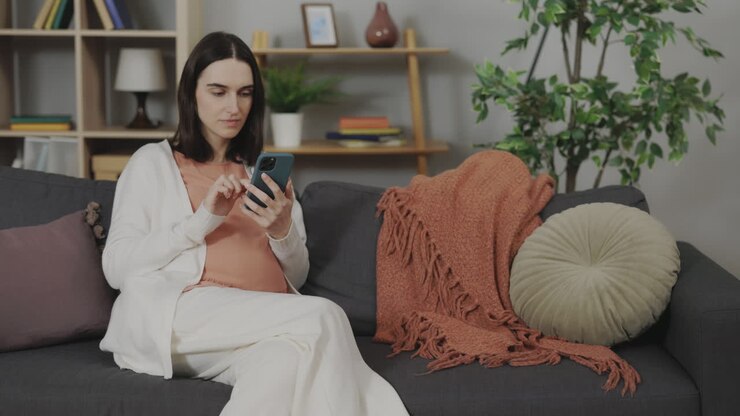 Pregnant Woman Using Smartphone on Sofa