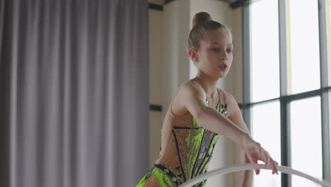 young girl in leotard practising rhythmic gymnastics with a ring in a studio 1