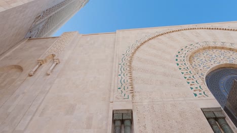 Hassan-II-Mosque-POV-looking-up-at-decorative-Moroccan-marble-tower-architecture-and-archway-entrance,-Casablanca