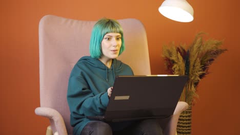 una mujer joven mira la computadora portátil y se alegra.