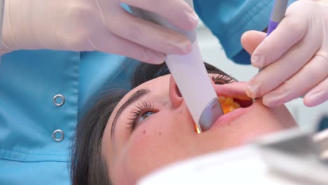 las manos del dentista sostienen el dispositivo de escaneo dental en la boca del paciente antes del tratamiento