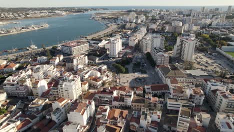 Aerial-wide-over-urban-cityscape,-Portimao-downtown-Buildings-by-the-Arade-river,-Portugal