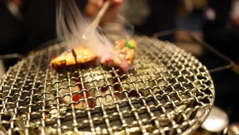 meat skewers being cooked on a round grill