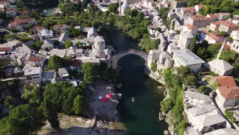 tourists on famous bridge stari most in balkan city mostar, aerial tilt up