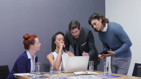 Group-of-executives-discussing-over-laptop-at-desk-4k