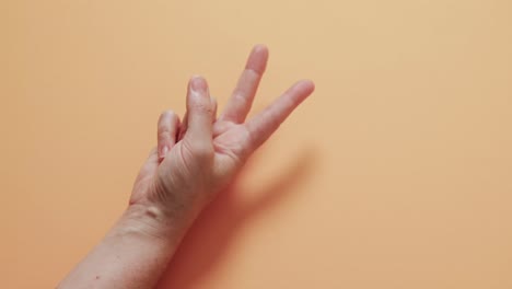 cerca de la mano de una mujer cacauana que muestra un signo de paz con espacio de copia en un fondo amarillo