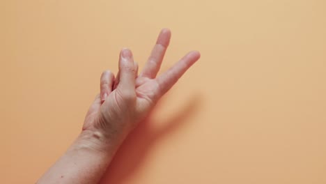 close up of hand of cacausian woman showing peace sign with copy space on yellow background