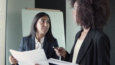 young pretty businesswomen discussing report and gesturing