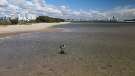 Un-Kayak-Flota-En-Agua-Clara-Rodeado-Por-Una-Isla-De-Arena-Natural-Cerca-De-Un-Concurrido-Lugar-De-Vacaciones-En-La-Costa