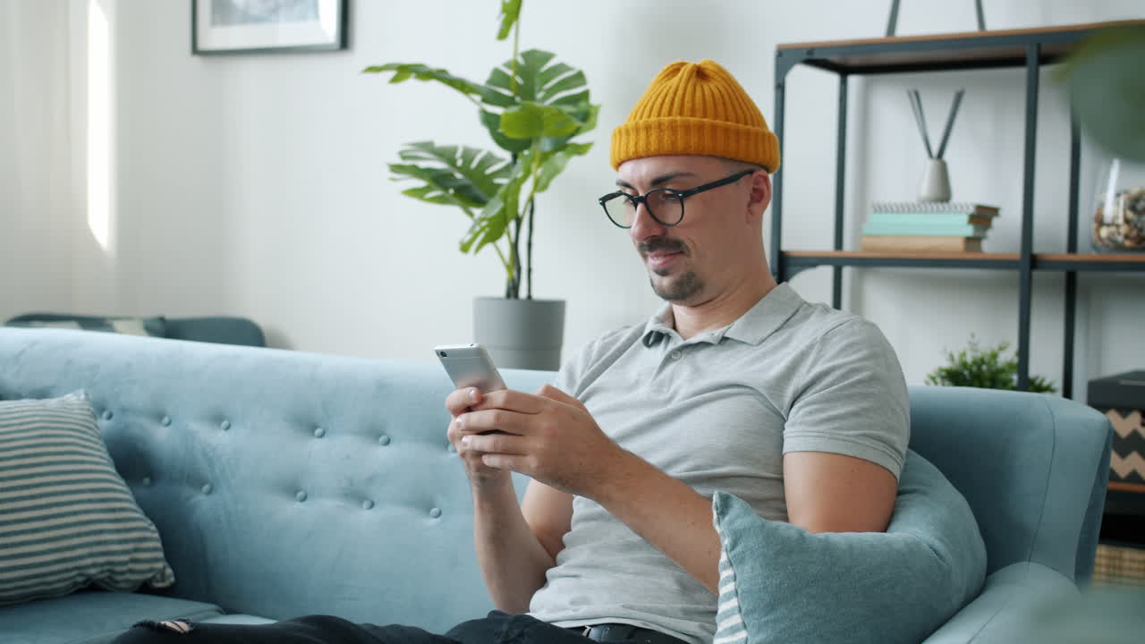 소파에서 스마트폰을 사용하는 남자
