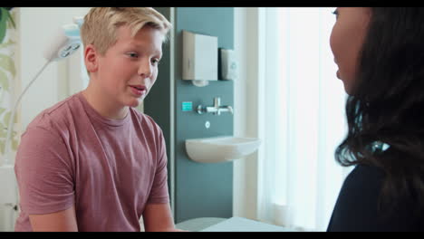 pediatric doctor examining teenage boy in surgery