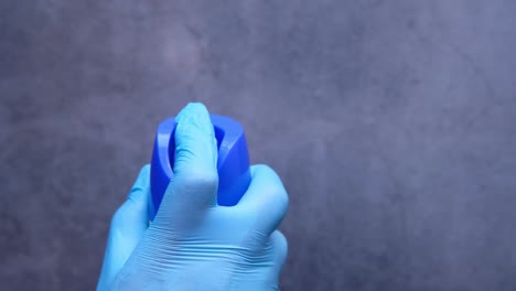 hand in gloves holding a blue spray bottle