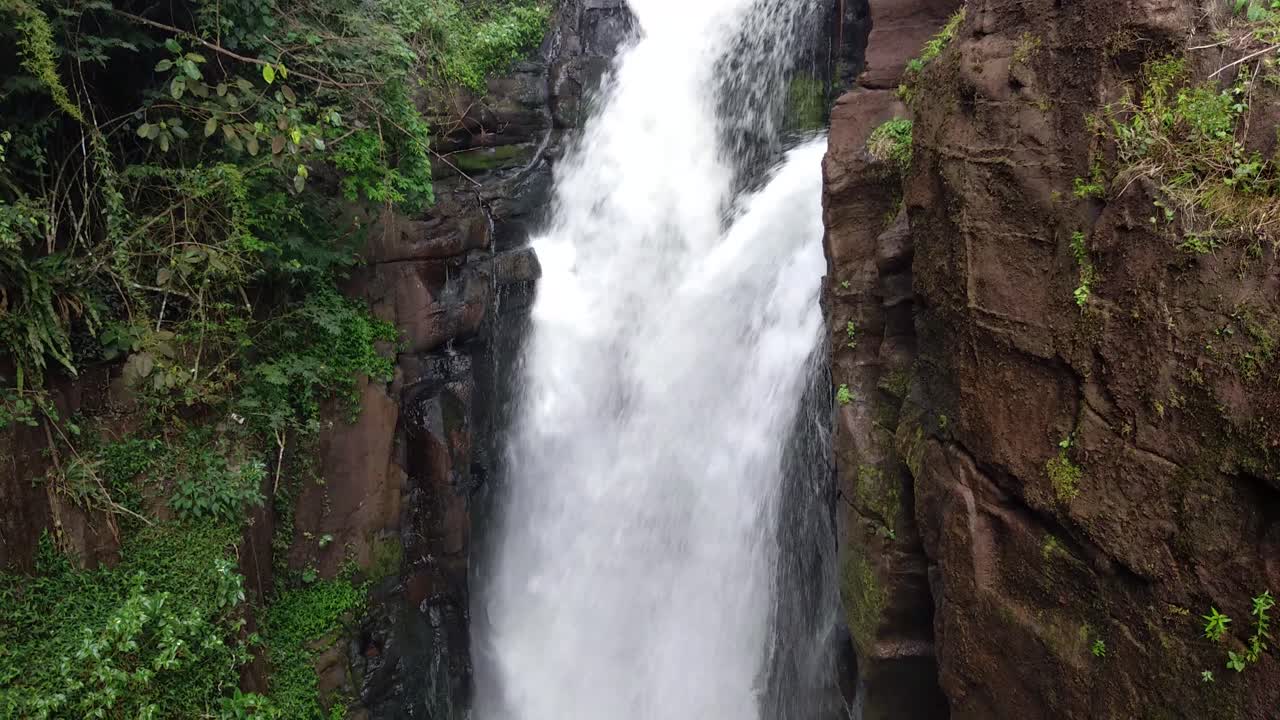panorámica hacia abajo de una fuerte cascada que fluye sobre un acantilado rocoso