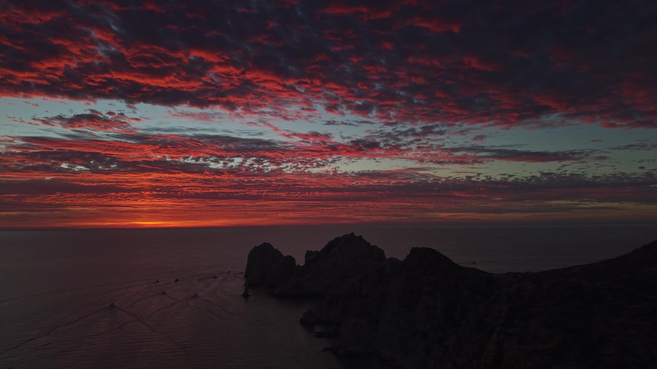 Luftaufnahme: Sonnenuntergang mit Abendrot und aufgetürmten Wolken über den Felsformationen von Cabo San Lucas, Mexiko.