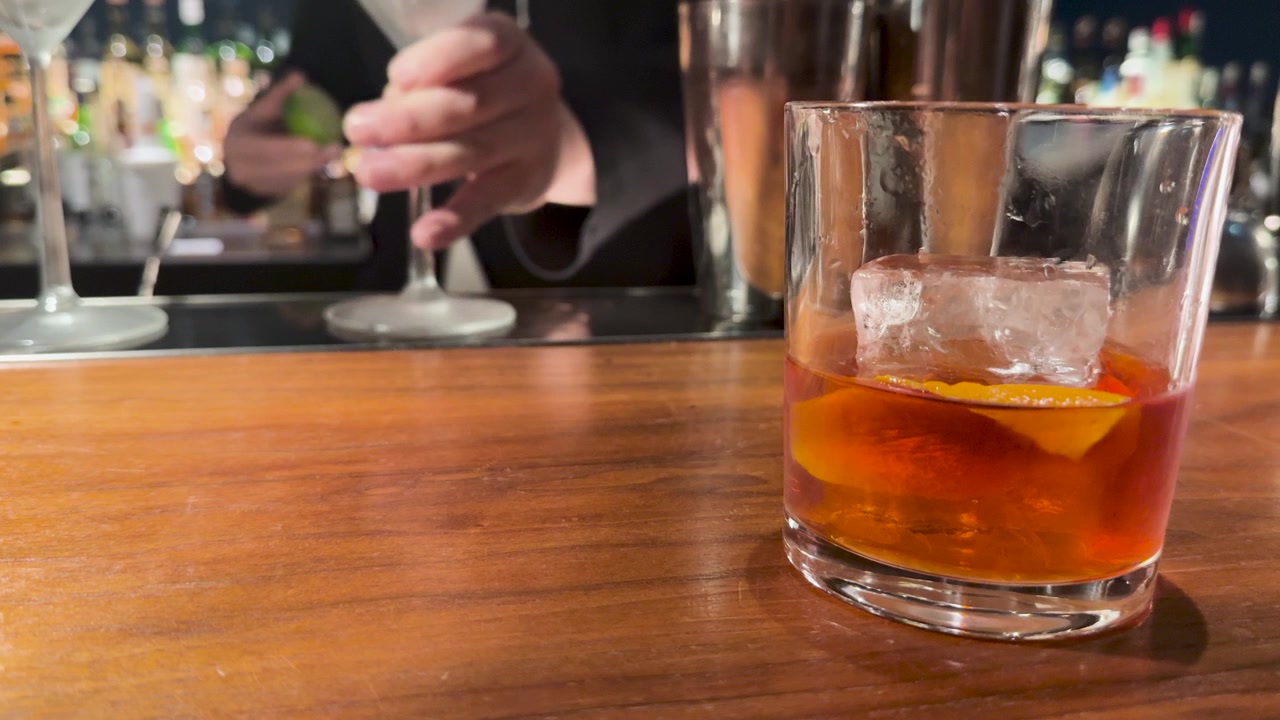 Primo piano di un cocktail al whisky con scorza d'arancia su un bancone di legno a Kanazawa.