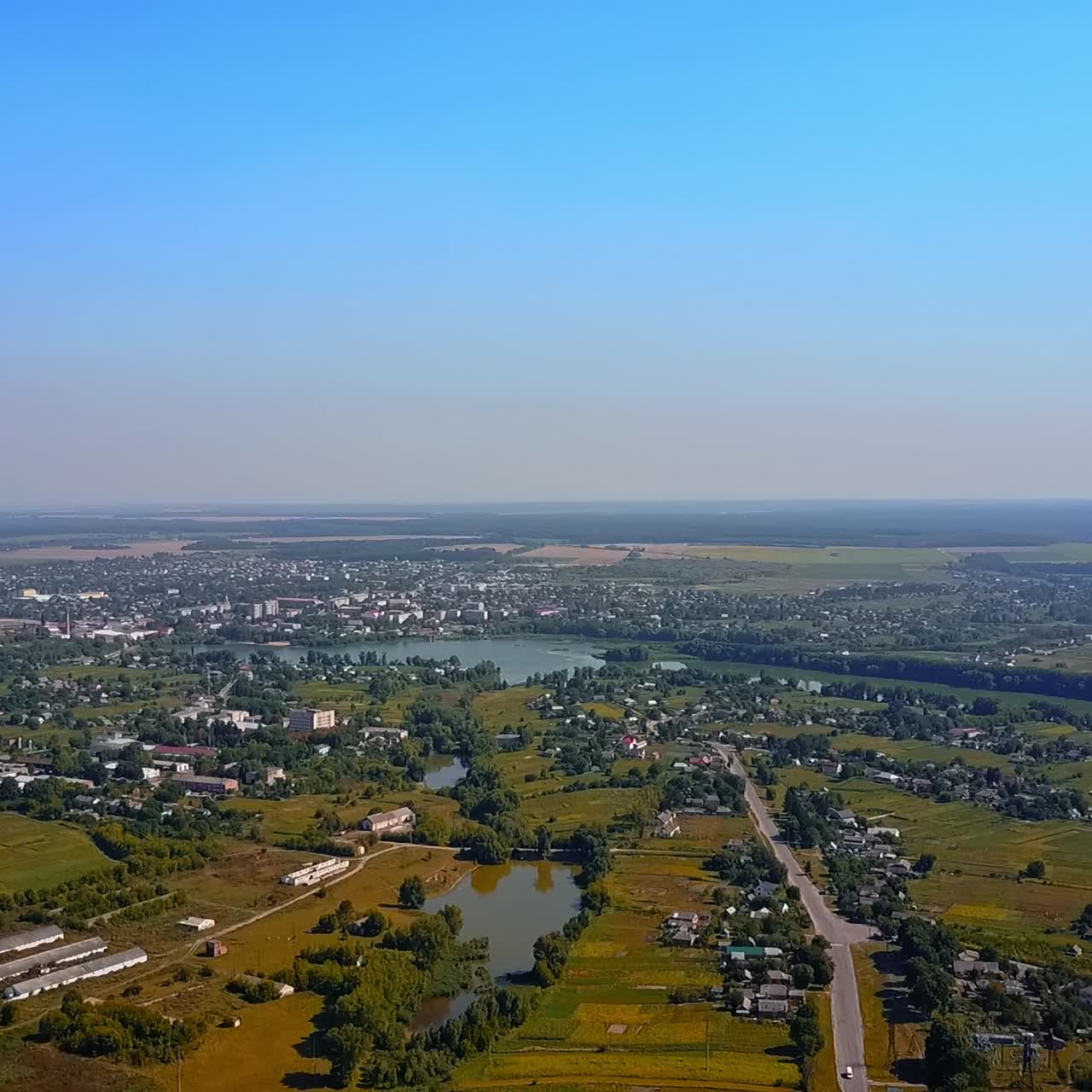 Beautiful scenery of countryside area on clear bright day. City view around the river at backdrop of blue sky. Top perspective