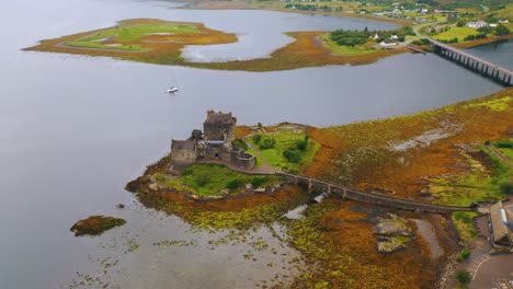 Birdseye-Aerial-View-of-Scottish-Castle-Eilean-Donan-on-Loch-Duich-in-Low-Tide-in-the-Scottish-Highlands,-Scotland,-United-Kingdom