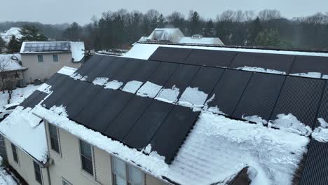 solar panels on snowy roof of house in american neighborhood at winter season