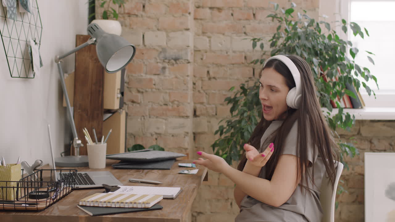 Woman Sitting at Desk and Dancing to Music