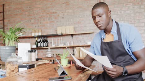 african american male coffee shop owner using tablet and doing paperwork, slow motion