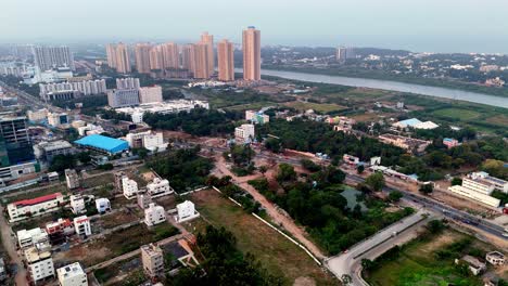 aerial view of india. a mix of developed and developing areas with modern high-rise buildings in the distance contrasting with low-rise residential houses and open plots expanding in an indian city