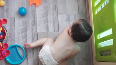 Slow-Motion-high-angle-shot-of-a-one-year-old-asian-boy-playing-by-himself-with-colorful-toys-inside-an-indoor-playground