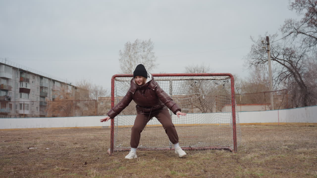 escena de entrenamiento de portero, portero practicando en un día de clima apagado, portería oxidada con portero practicando reflejos, portero perfeccionando la reacción y técnicas de postura durante un día nublado en la ciudad