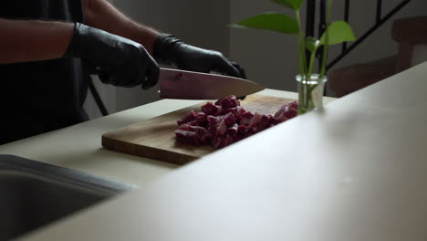 Chef-is-dicing-the-most-delicious-fresh-chuck-of-beef,-using-black-gloves-and-sharp-chef-knife