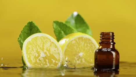 lemon halves and bottle in water close-up, lemon juice. raining, aroma serum on yellow background. liquid citrus extract, skincare routine, treatment spa concept. traditional medicine